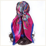 Foulard carré en satin aux motifs de plumes multicolores sur fond rose vif
