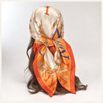 Foulard carré en satin aux motifs chaînes dorées et touches d’orange vif