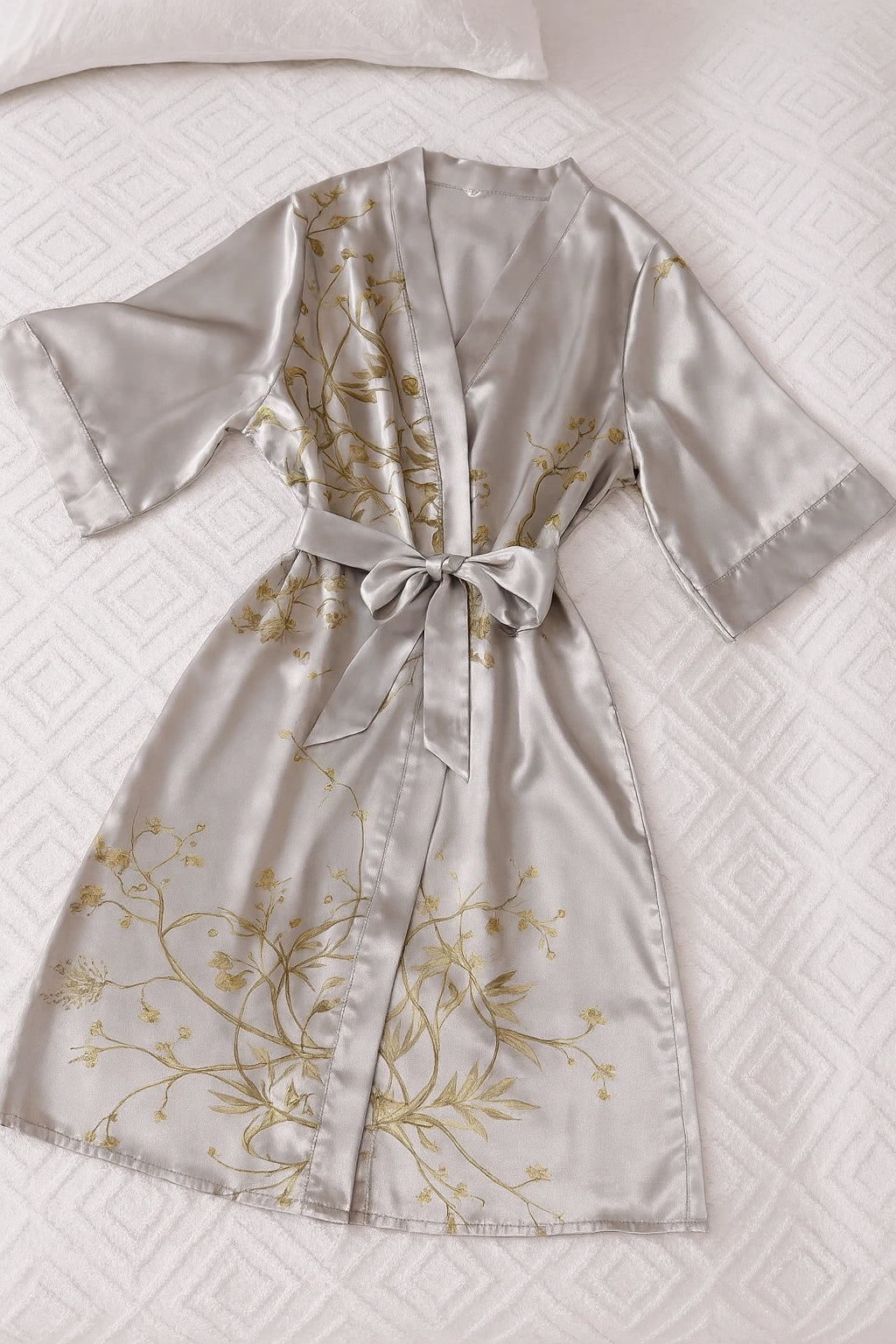 Un élégant kimono en satin gris clair délicatement posé sur un lit