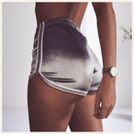 Une femme portant un pyjama short en satin gris dégradé, photographiée de dos dans un intérieur lumineux et épuré