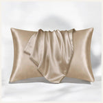 une taie d'oreiller en satin beige élégamment disposée sur un fond blanc, mettant en valeur sa douceur et son éclat raffiné.