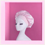 Présentation d'un bonnet en satin rose, élégamment disposé sur un fond rose, mettant en valeur son éclat soyeux et son raffinement.