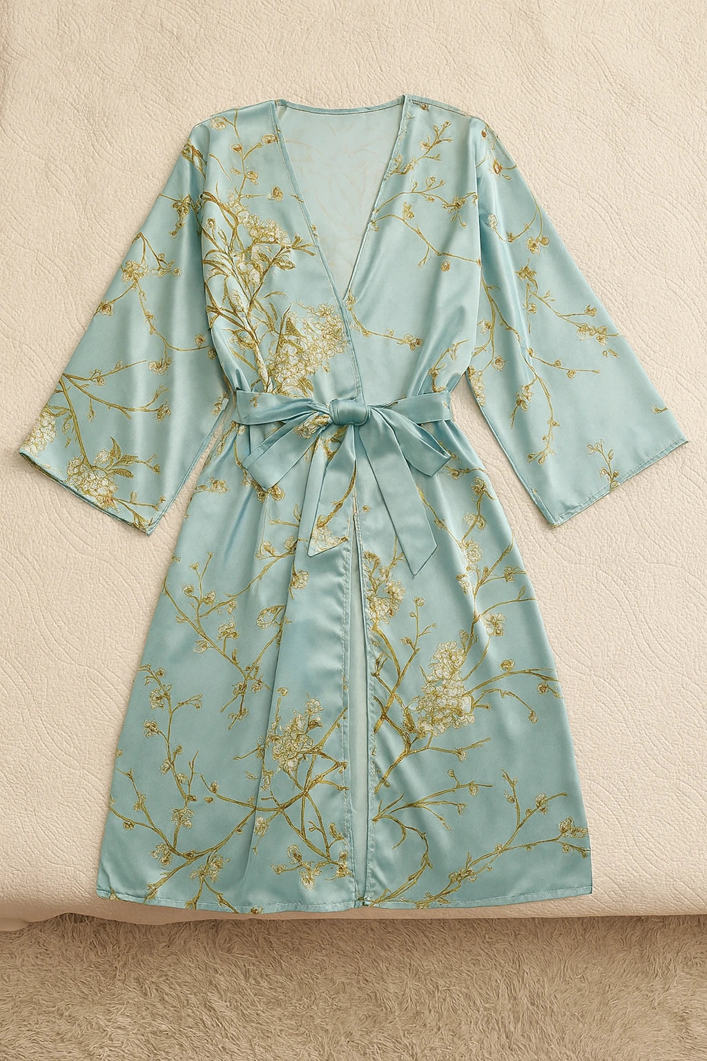 Un kimono en satin vert clair délicatement posé sur un lit immaculé